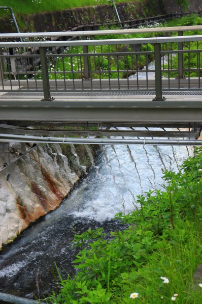 白濁した石灰水が温泉の流れる川に投入されています。